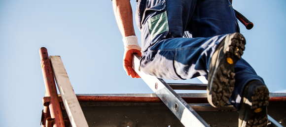 Contractor climbing a ladder at a worksite.